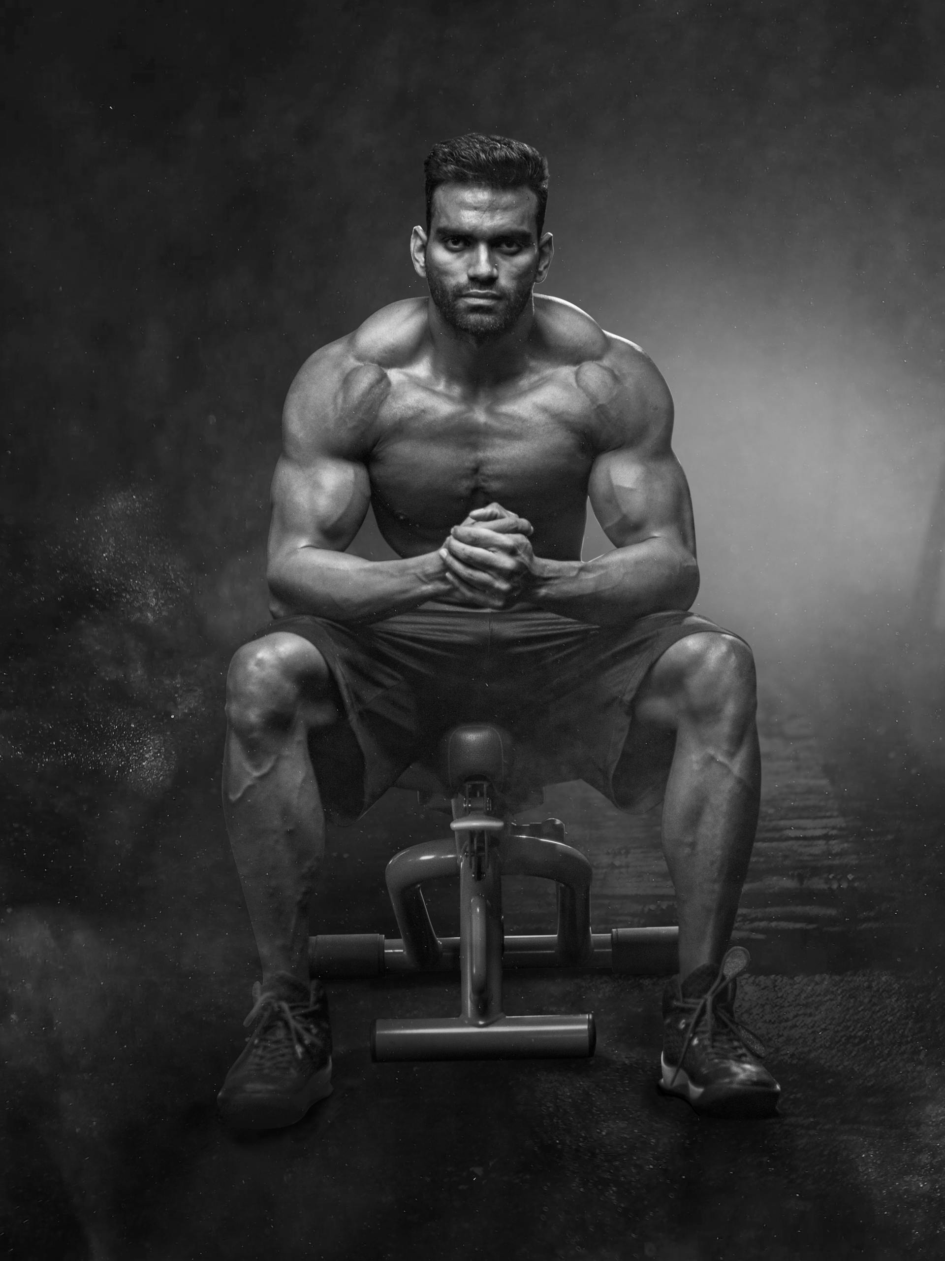 Strong man black and white image sitting on gym bench