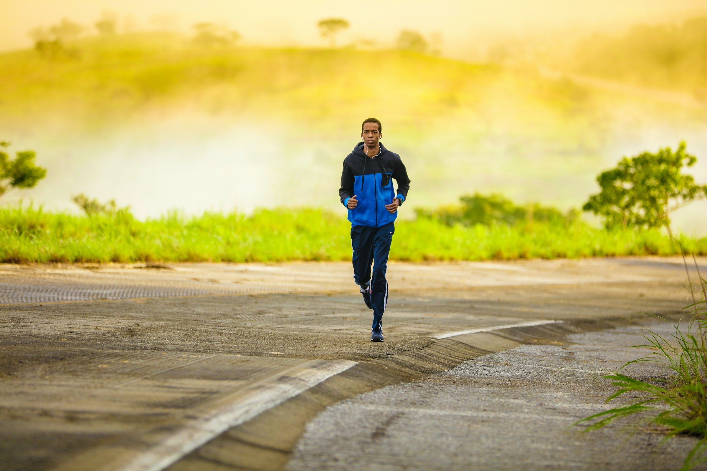 man wearing black and blue jacket running outdoors in nature